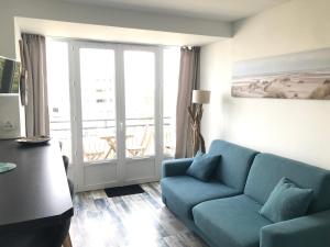 a living room with a blue couch and a balcony at Appartement Royan, 200 m de la PLAGE in Royan