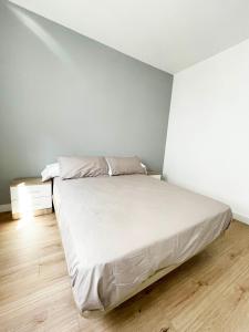 a bedroom with a white bed and a wooden floor at Apartamento San Isidoro in Santiago de Compostela