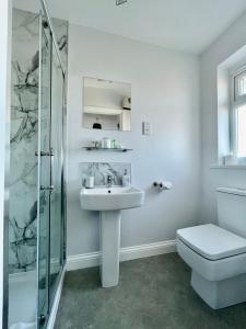 y baño blanco con lavabo y ducha. en Bojangles Guest House en Gretna Green
