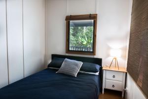 Noosa Rural Retreat في Pomona: غرفة نوم صغيرة بسرير ازرق ونافذة