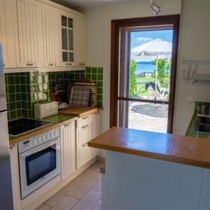 une cuisine avec des placards blancs, une fenêtre et un comptoir dans l'établissement Alemar Estates Ouranoupolis, à Ouranoupoli