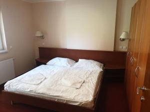 Una cama con sábanas blancas y almohadas en un dormitorio en Aparthotel Rosa - apartma 204, en Podčetrtek