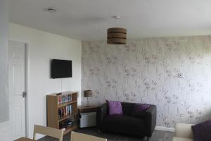 a living room with a couch and a wall with flowers at 78 Florida Holiday Park in Hemsby
