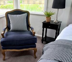 a bedroom with a blue chair next to a bed at Hunter Cottage Euroa in Euroa