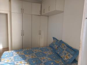 a bedroom with a bed with a blue quilt and white cabinets at SEU CANTINHO NA BARRA in Rio de Janeiro