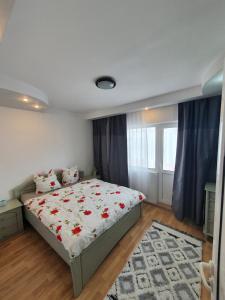a bedroom with a bed with red flowers on it at Mândra Apartaments in Curtea de Argeş