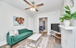 a living room with a green couch and a tv at 1 Bd Apt near forest park, Science Center & dining in Tower Grove