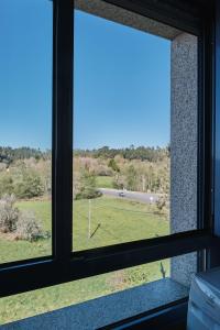 a window with a view of a field outside at Peregrina Pensión 1 in O Pedrouzo