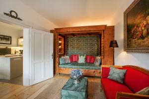 a living room with a red couch and a table at Garden Cottage Villa Lichtenstein - Your Austrian Home in Altaussee