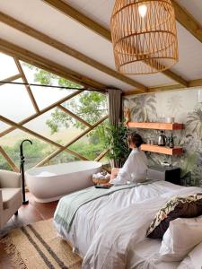 eine Frau auf einem Bett in einem Schlafzimmer mit Badewanne in der Unterkunft Quaint Luxury Villas in Graskop