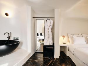 a bedroom with a black tub and a bed and a sink at Abyss in Oia