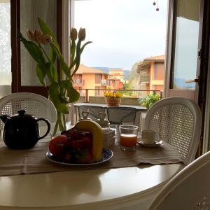 un tavolo con un piatto di frutta e un bicchiere di succo d'arancia di Elena Apartment Residence a Bardolino