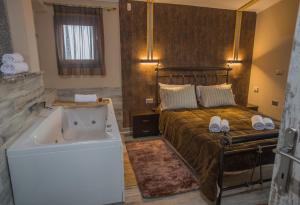 1 dormitorio con cama y bañera en ΒΙΛΛΑ ΤΟ ΠΕΤΡΙΝΟ stone bild villa full equipment, en Nafpaktos