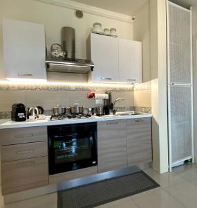 una cucina con armadi bianchi e piano cottura di Elena Apartment Residence a Bardolino