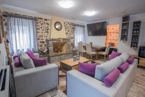 a living room with two couches and a fireplace at ΒΙΛΛΑ ΤΟ ΠΕΤΡΙΝΟ stone bild villa full equipment in Nafpaktos