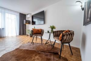 ein Wohnzimmer mit 2 Stühlen und einem Tisch in der Unterkunft City Wohnung FN L 5 KLIMATISIERT mit Balkon und Küche in Friedrichshafen