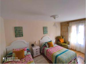 a bedroom with two beds and a chair at Casa Pepa in Corcubión +3 photos