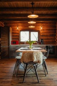 a dining room with a table with chairs and a kitchen at Poeme Chalet in Râșca