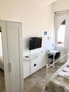 a white room with a tv and a desk with a computer at B&B Il Poeta sul Mare in Ancona