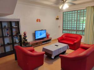 salon z 2 czerwonymi krzesłami i telewizorem w obiekcie NH Homestay Sibu w mieście Sibu