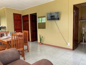 sala de estar con mesa y TV en la pared en Blue House, en Puerto Jiménez