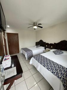 a room with two beds and a ceiling fan at Hotel California in Tuxpan de Rodríguez Cano