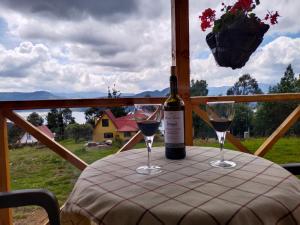a bottle of wine sitting on a table with two glasses at Cabaña Los Girasoles in Guatavita