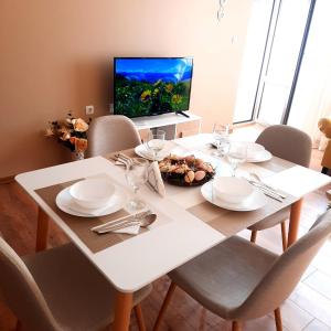 a white dining room table with chairs and a television at Апартамент Лидия in Chepelare