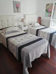 1 dormitorio con 2 camas con sábanas blancas y negras en Pensión Casa Frade, en Arzúa