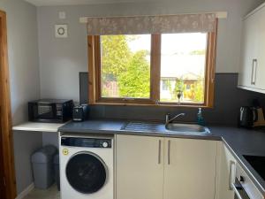 a kitchen with a washing machine and a window at The Wee Hoose near Loch Ness, private garden, private parking in Drumnadrochit