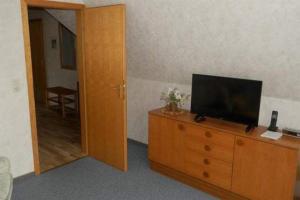 Zimmer mit TV auf einer hölzernen Kommode mit Tür in der Unterkunft Wohnung Lund 2 in Wyk auf Föhr
