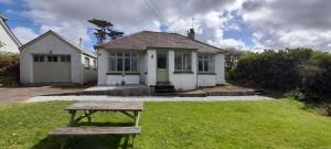 a small white house with a picnic table in the yard at Perranporth Bungalow 2mins Walk to Beach! in Perranporth