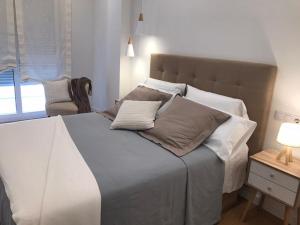 una camera da letto con un grande letto con cuscini sopra di Apartamento Palacio Valdés, centro Avilés, con parking ad Avilés