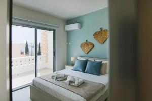 Schlafzimmer mit einem Bett mit blauen Wänden und einem Fenster in der Unterkunft Phaedrus Living: City View Fountain Court 113 in Ayia Napa