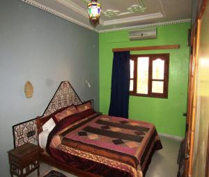 a bedroom with a bed with green walls and a window at La Perle Du Drâa in Zagora