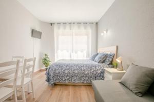 a white bedroom with a bed and a window at Apartment 233 Hispalis Triana in Seville