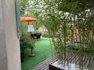 une terrasse avec une pelouse dotée d'un parasol et d'une chaise. dans l'établissement Appartement cosy en centre ville avec SPA et jardin, à Dijon