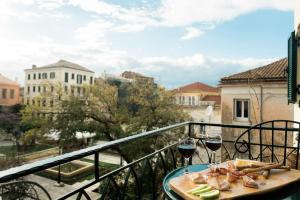 um prato de comida e dois copos de vinho numa varanda em Deluxe Town Hall Square Flat in Historical Center 2 em Corfu Town