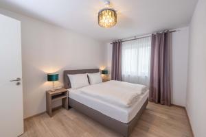 1 dormitorio con cama blanca y ventana en City Wohnung Relax 3 klimatisiert, en Friedrichshafen