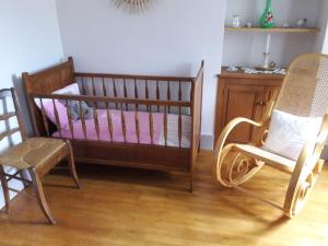 a crib and two chairs in a room at La maison du Mas Rando in Saint-Georges-Nigremont
