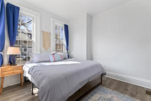 1 dormitorio con 1 cama y una ventana con cortinas azules en Casa Soleada in East Rock near DT and Yale SOM with FREE Parking and King Bed, en New Haven