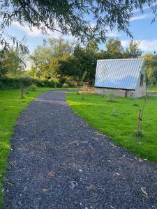 une route en gravier menant à une maison au toit bleu dans l'établissement Countryside Cabin, à Taunton