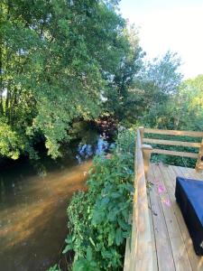 a bench sitting on a wooden bridge next to a river at Countryside Cabin in Taunton