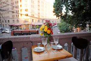 a table with glasses and a vase of flowers on a balcony at Cozy Apartment on Republic Square in Yerevan