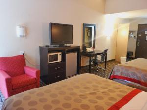 a hotel room with a bed and a tv and a chair at Ramada by Wyndham Grand Junction in Grand Junction