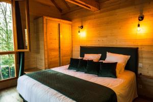 1 dormitorio con 1 cama en una cabaña de madera en Charmante Cabane dans les arbres avec jacuzzi et sauna en Boismorand