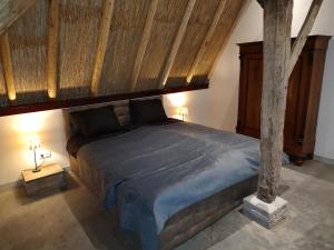 een slaapkamer met een groot bed en een houten plafond bij Juweeltje van vakantiewoning op prachtig landgoed in Nieuwleusen