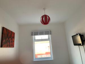 um quarto com uma janela e uma luz pendente em Starlight Self Service Accommodation em Leigh