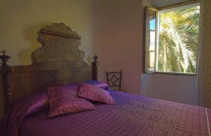 a bedroom with a purple bed with pillows and a window at Hostal Miramar in Deia