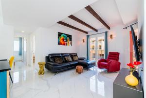 a living room with a black leather couch and two red chairs at Apartamento Torrevieja Sunrise Atalayas in Torrevieja